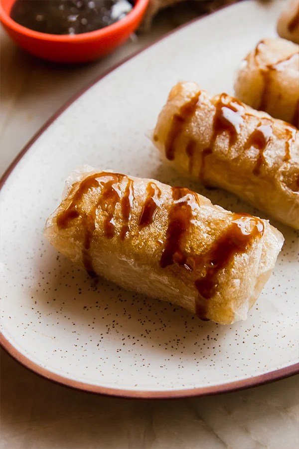 Caramel apple rice paper rolls topped with caramel sauce.