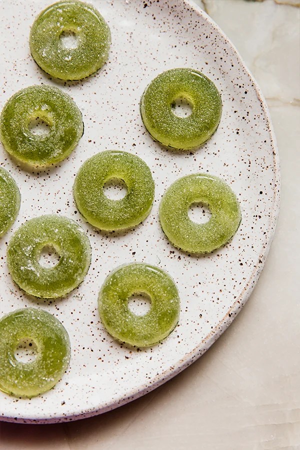 Plate with several sour apple ring gummies.
