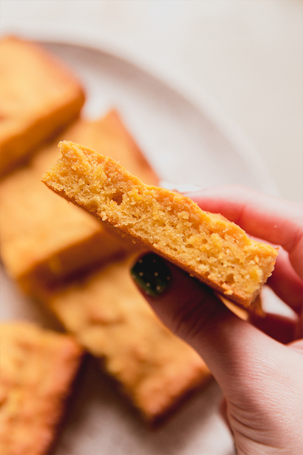 Person holding a piece of \"corn\" bread.