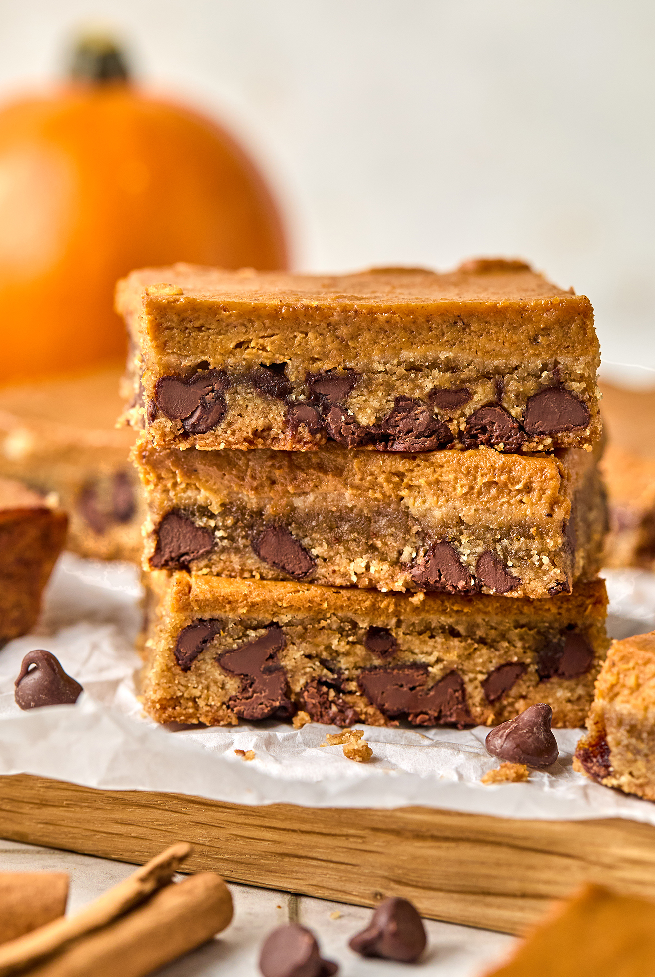 Three pumpkin cookie bars stacked on top of each other with a pumpkin in the background.