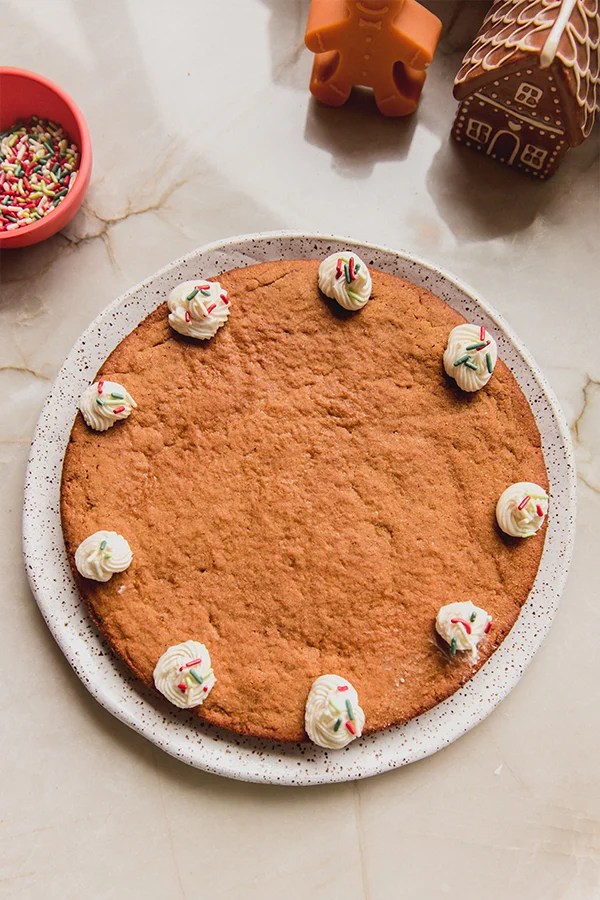 Gingerbread cookie cake with dollops of whipped cream on a plate.