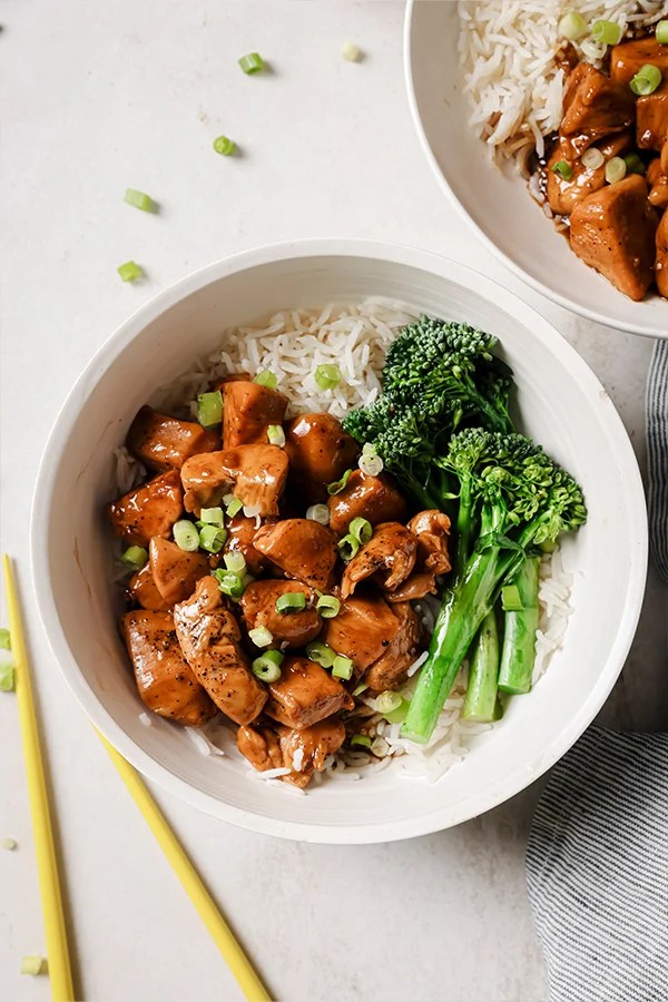 Rice, broccolini, and bourbon chicken in a dish.