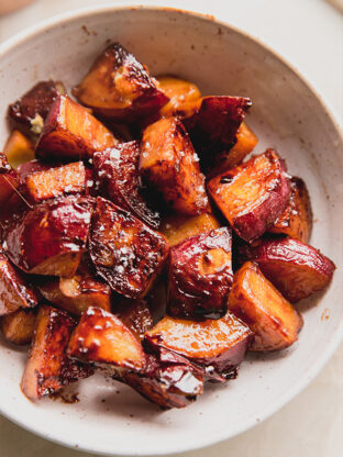Candied sweet potatoes in a bowl topped with salt.