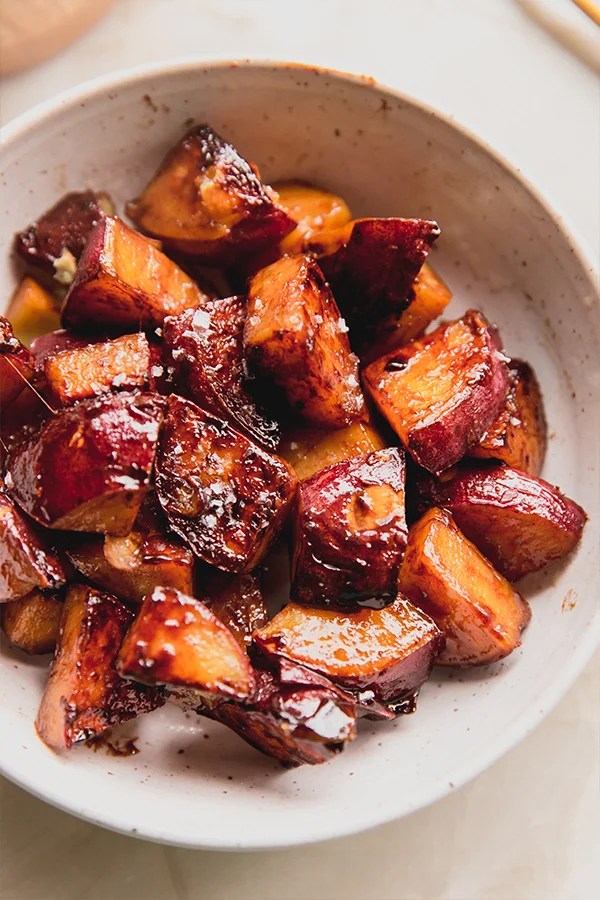 Candied sweet potatoes in a bowl topped with salt.