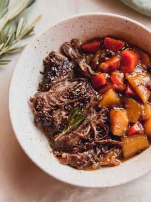 Carrots, parsnips, and cider-braised pot roast in a dish.