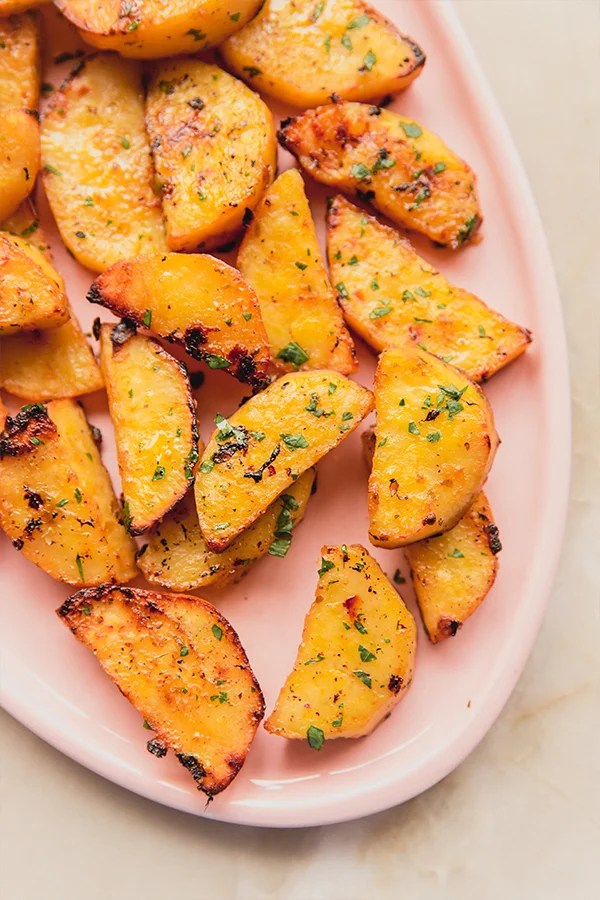 Greek lemon sweet potatoes on a pink plate.