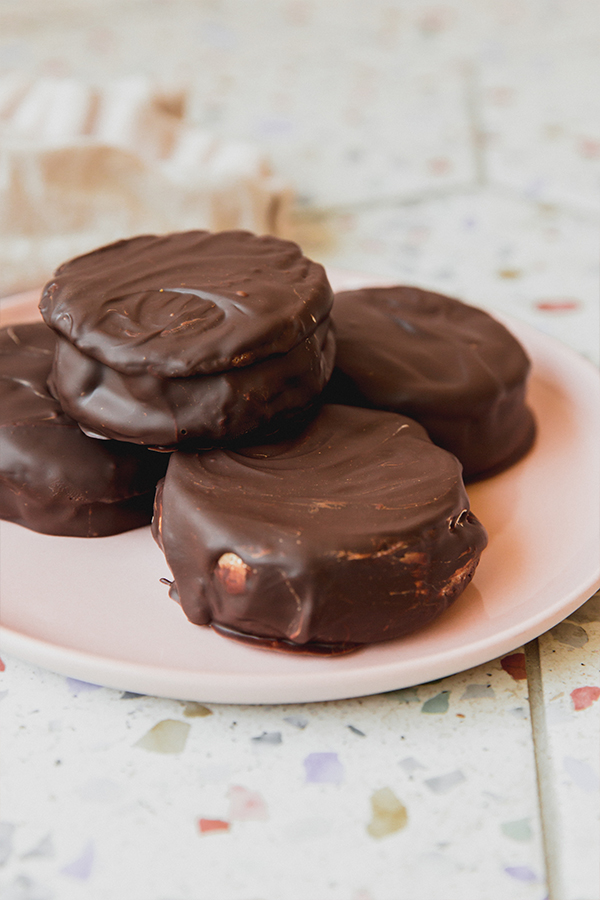 Four gluten free moon pies stacked on a pink plate.
