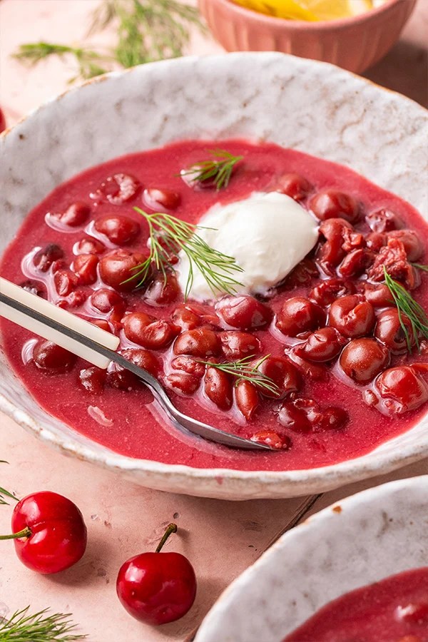 Bowl of Hungarian cold cherry soup with a spoon.