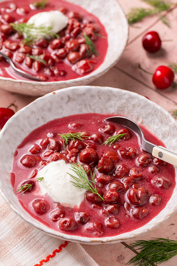 Spoon scooping from a bowl of Hungarian cold cherry soup.