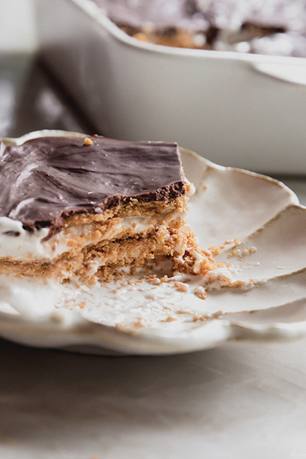 Gluten free eclair cake on a plate with a piece cut out.