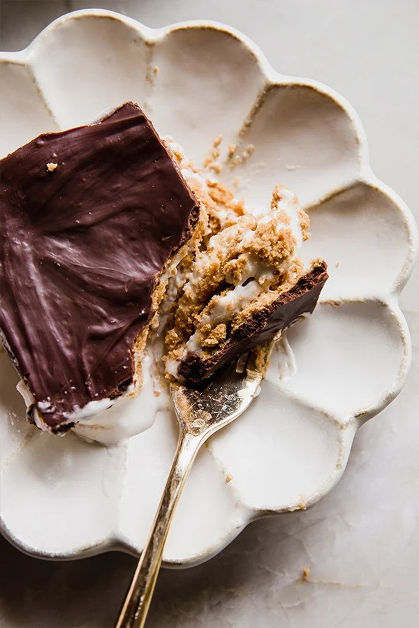 A slice of eclair cake on a plate, with a fork cutting a slice to show the layers of the cake.