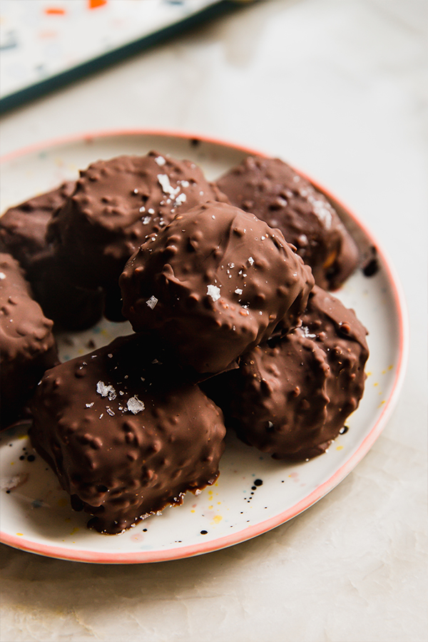 Dairy free strawberry crunch bites on a plate, topped with flakey salt.