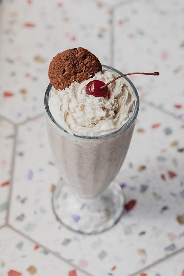 Ninja creami milkshake topped with whipped cream, a cookie and a cherry.