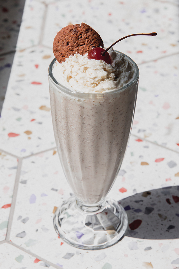 Ninja creami milkshake topped with whipped cream, a cookie and a cherry.