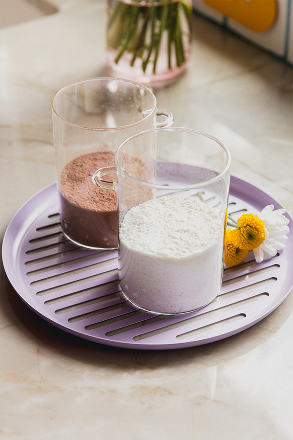 Chocolate and vanilla pudding mix in separate glasses, on a purple plate.