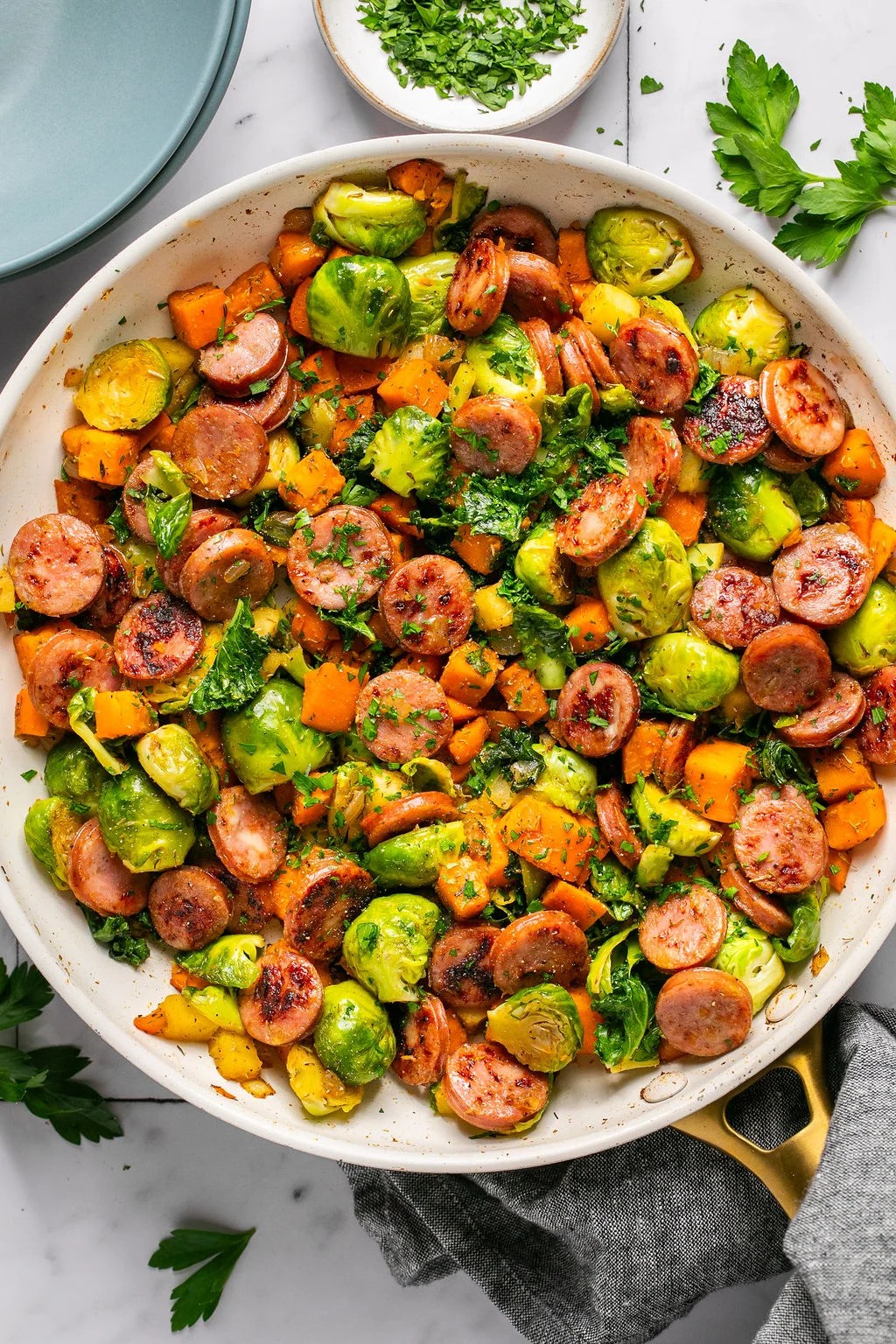 Apple, chicken sausage, and colorful vegetables in a large white bowl.