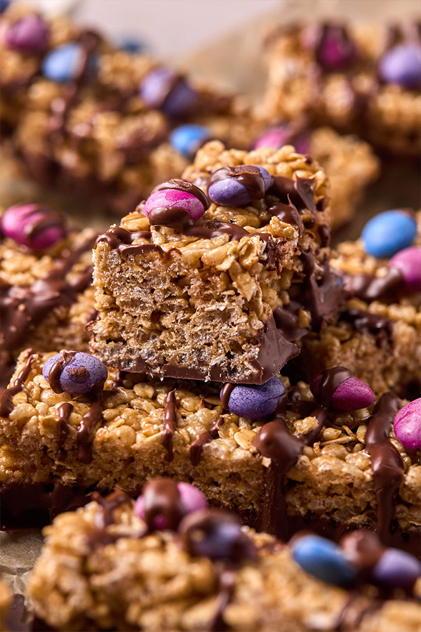 Kudos bars with candy on top and melted chocolate, stacked on top of eachother.
