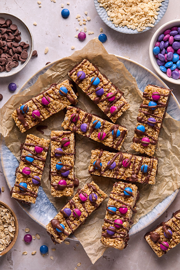 Kudos bars topped with candy gems and chocolate laid out on a platter.