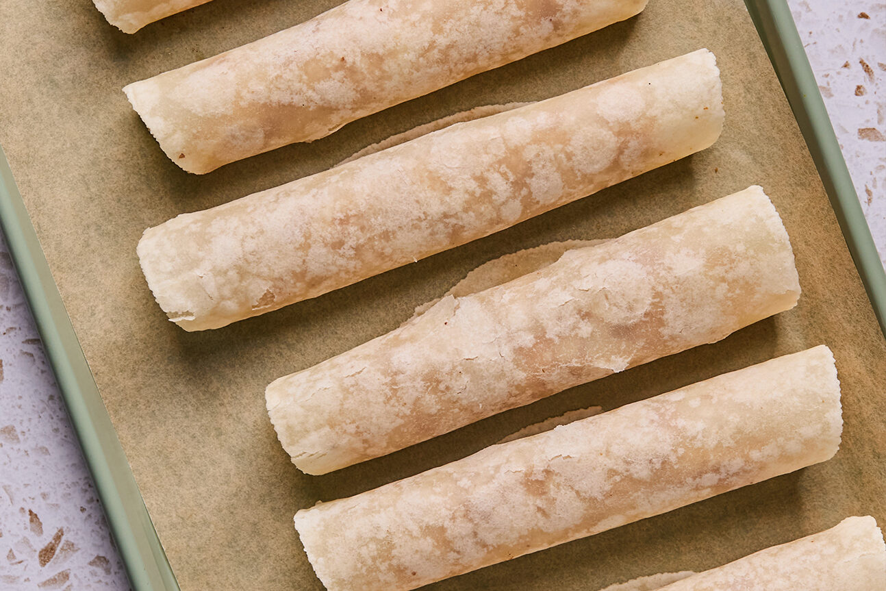 Apple pie roll ups rolled on a baking sheet.