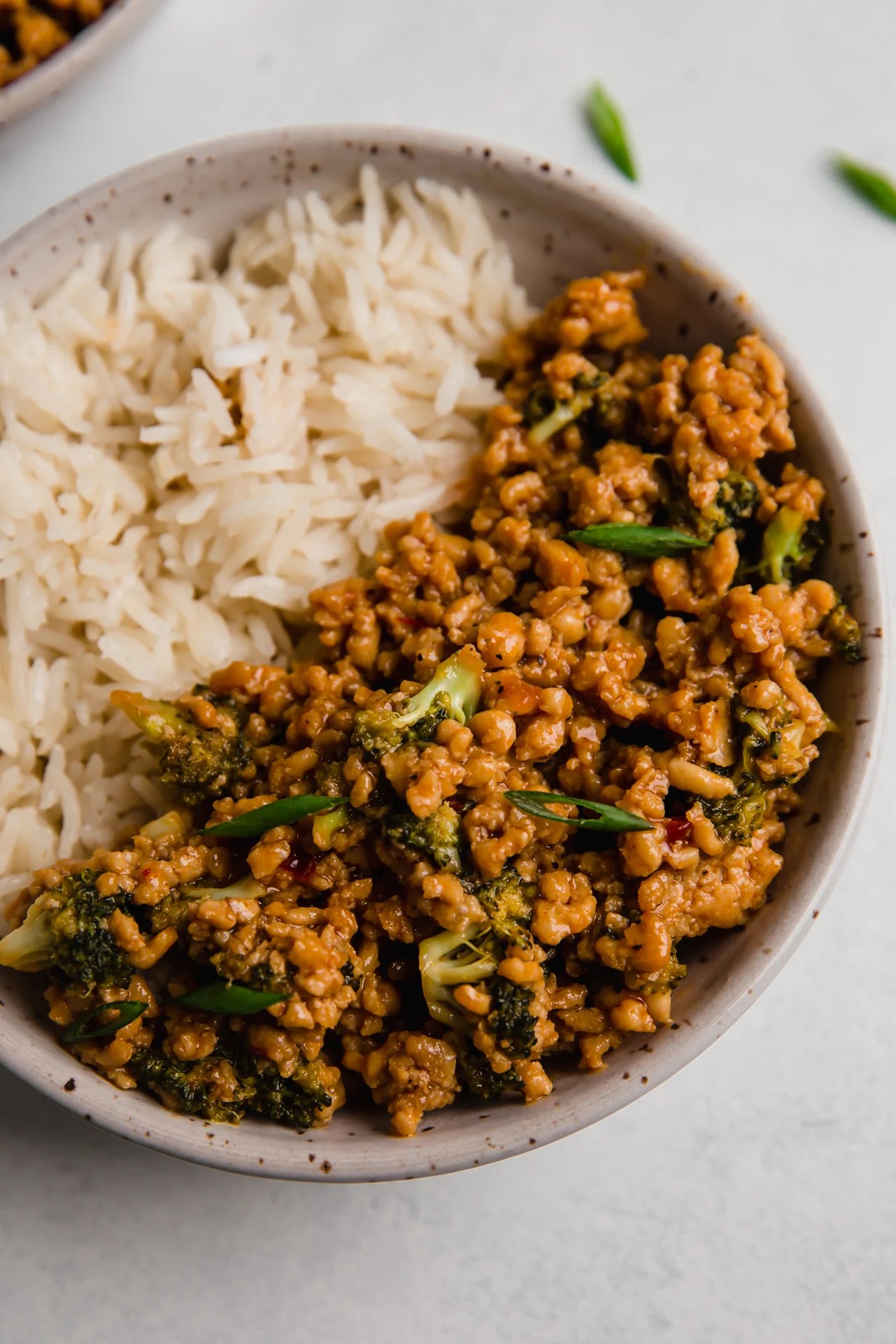 Firecracker ground chicken bowls topped with green onion and served with rice.