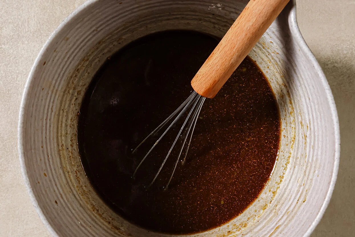Sauce for ground beef and broccoli in a bowl with a whisk.