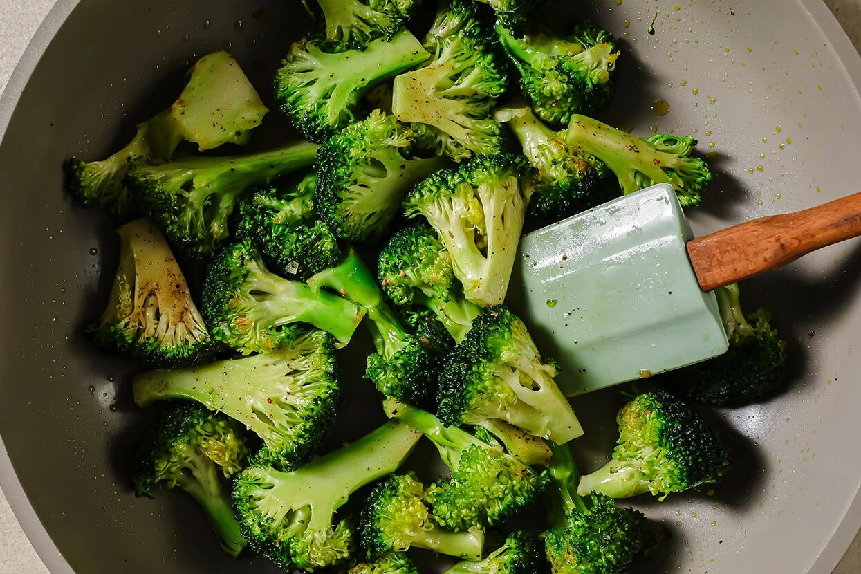 Broccoli sautéing in a pan.