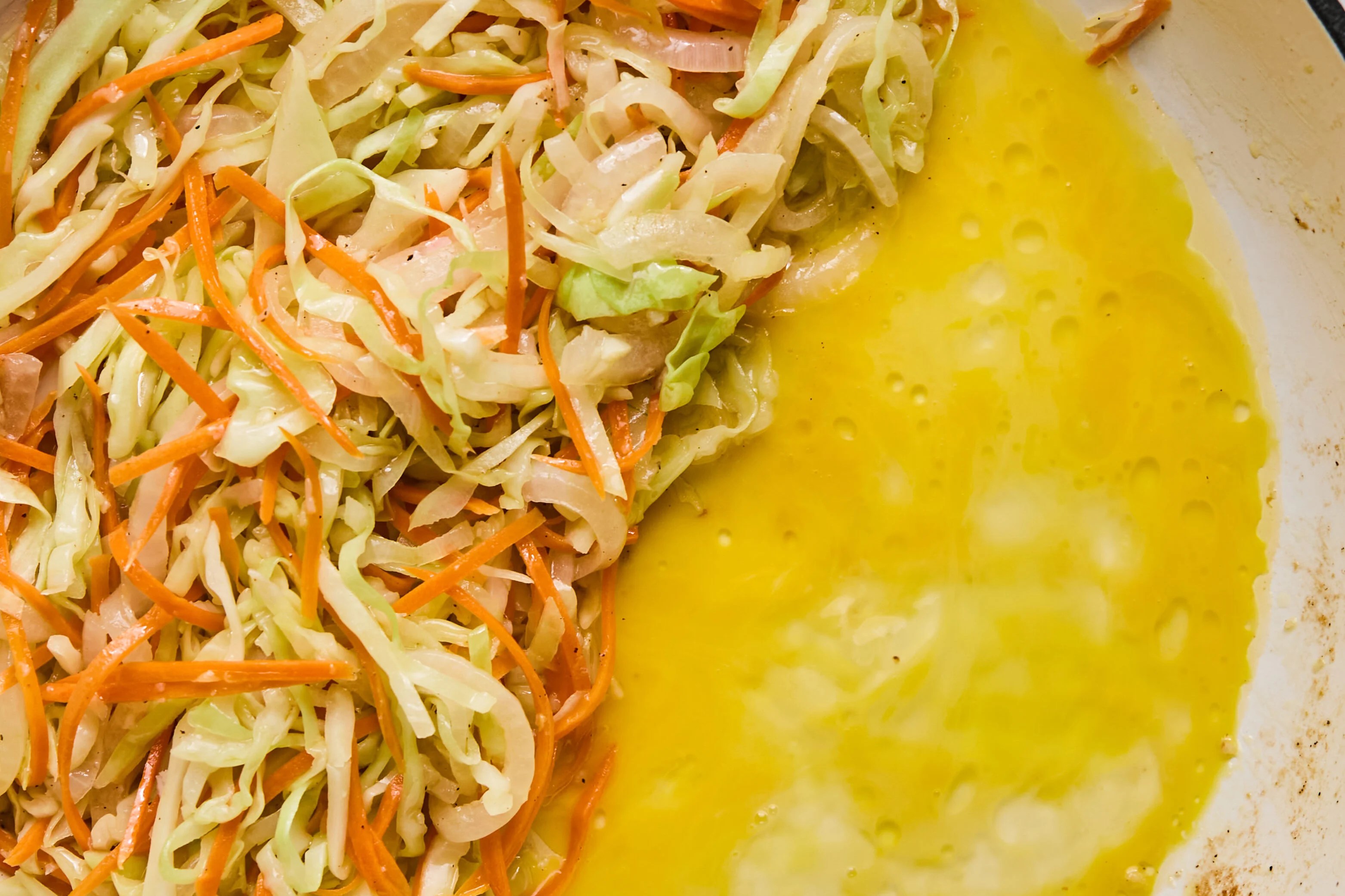 Whisked egg in a pan with vegetables.