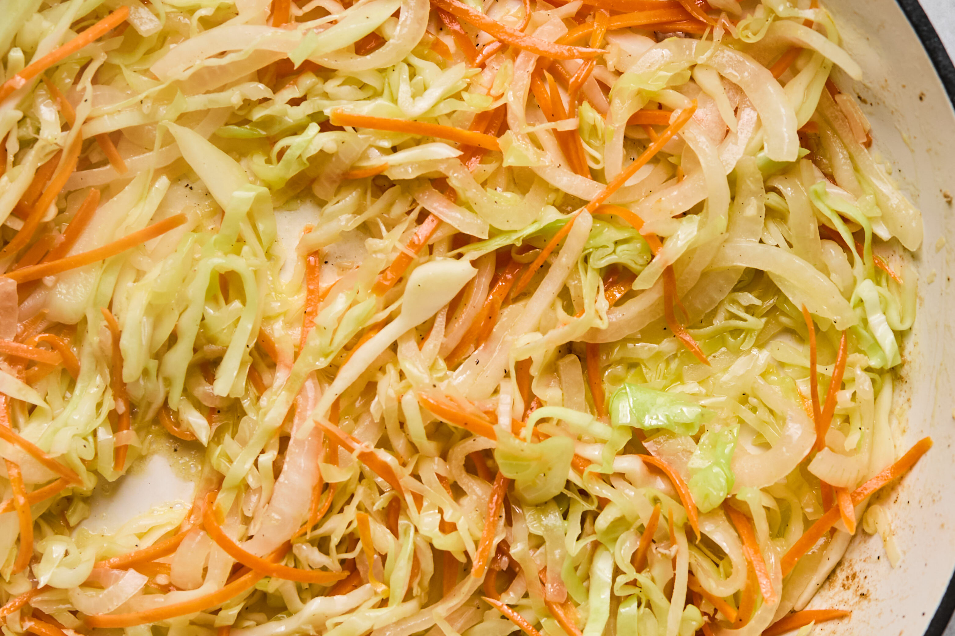 Cabbage, onion and carrots cooked in a pan.