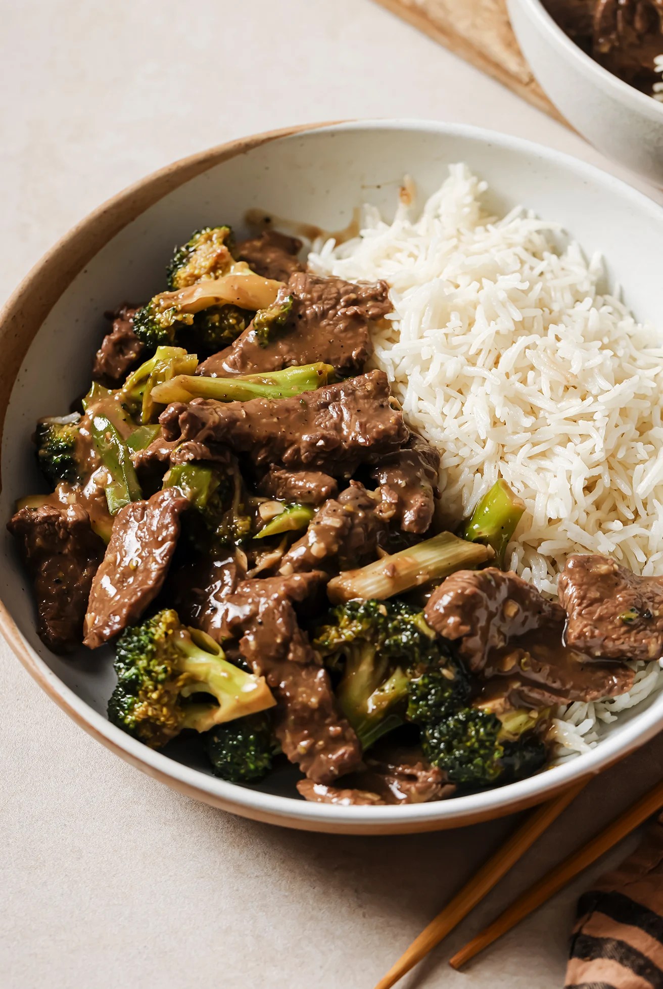 Gluten free mongolian beef and broccoli with a side of rice in a bowl.