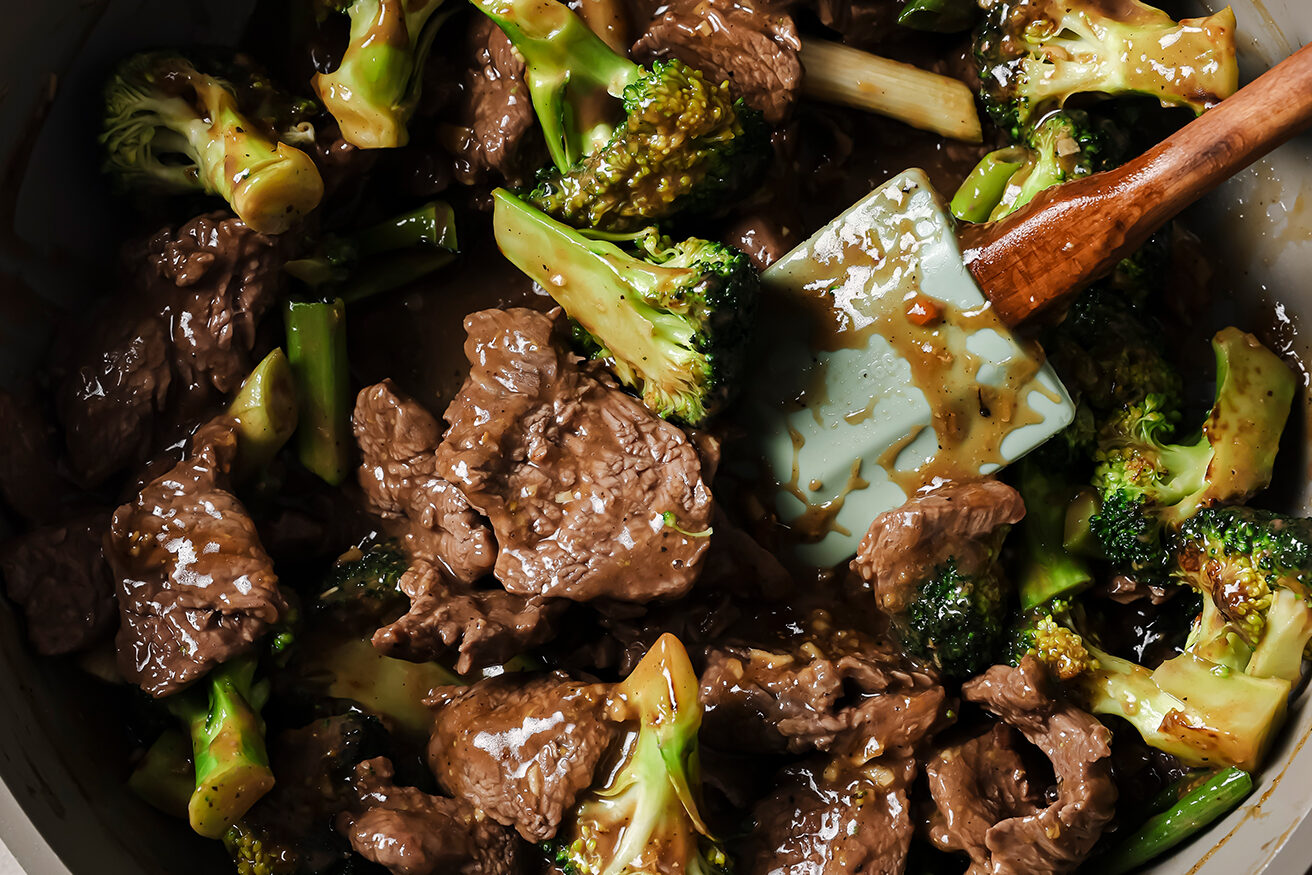 Cooked gluten free mongolian beef with sauce and broccoli in a pan.
