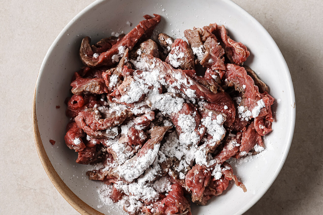 Sliced steak topped with arrowroot starch, ready to toss.