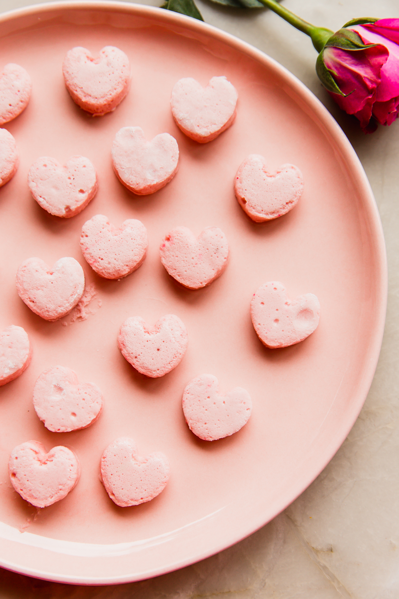 Pink heart shaped marshmallows on a pink plate.