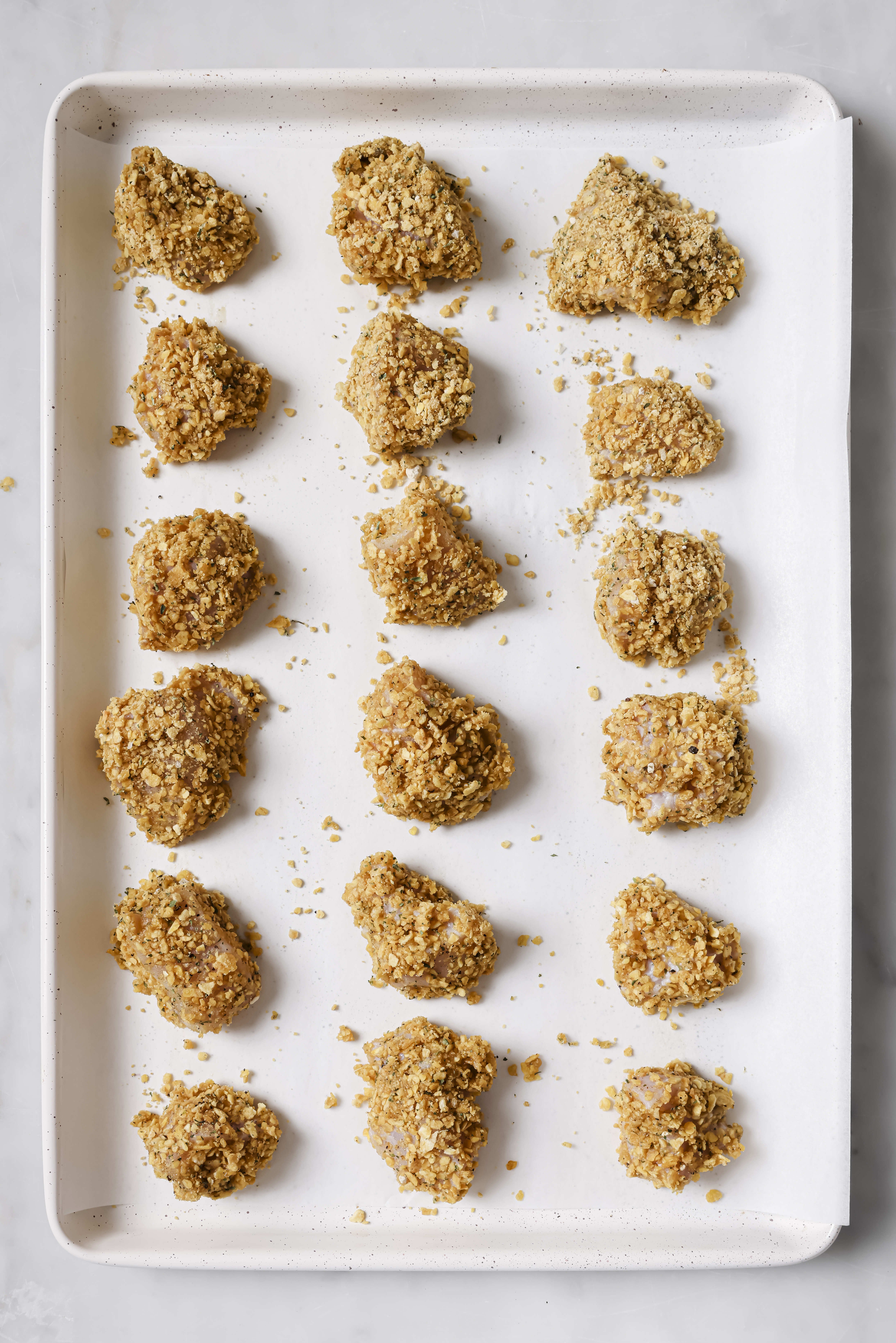 coated chicken nuggets on a parchment lined baking sheet