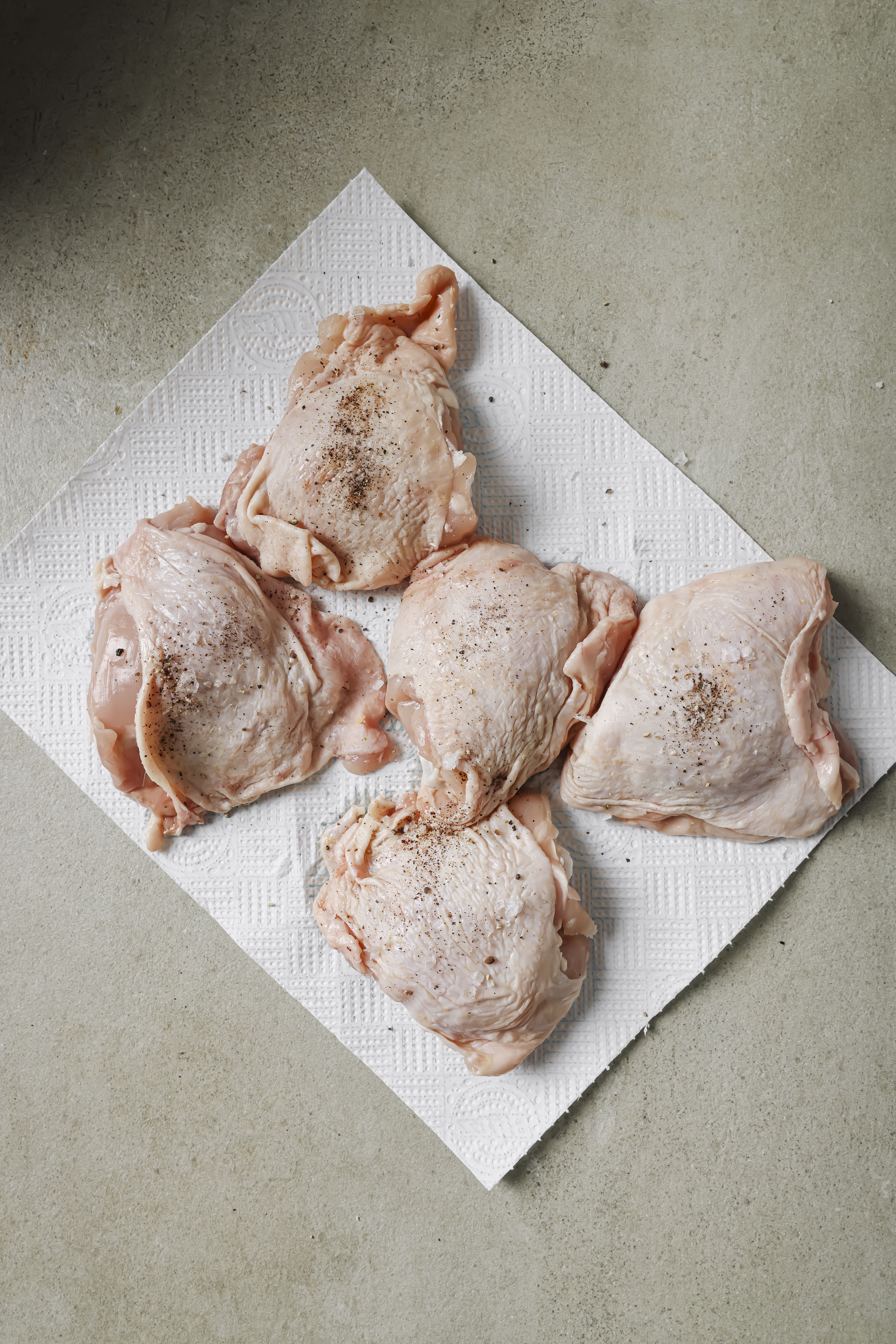 Seasoned raw chicken on paper towel.