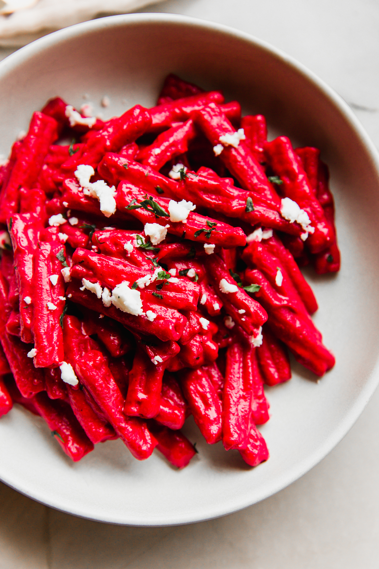 Pasta with beet sauce topped with goat cheese and parsley.