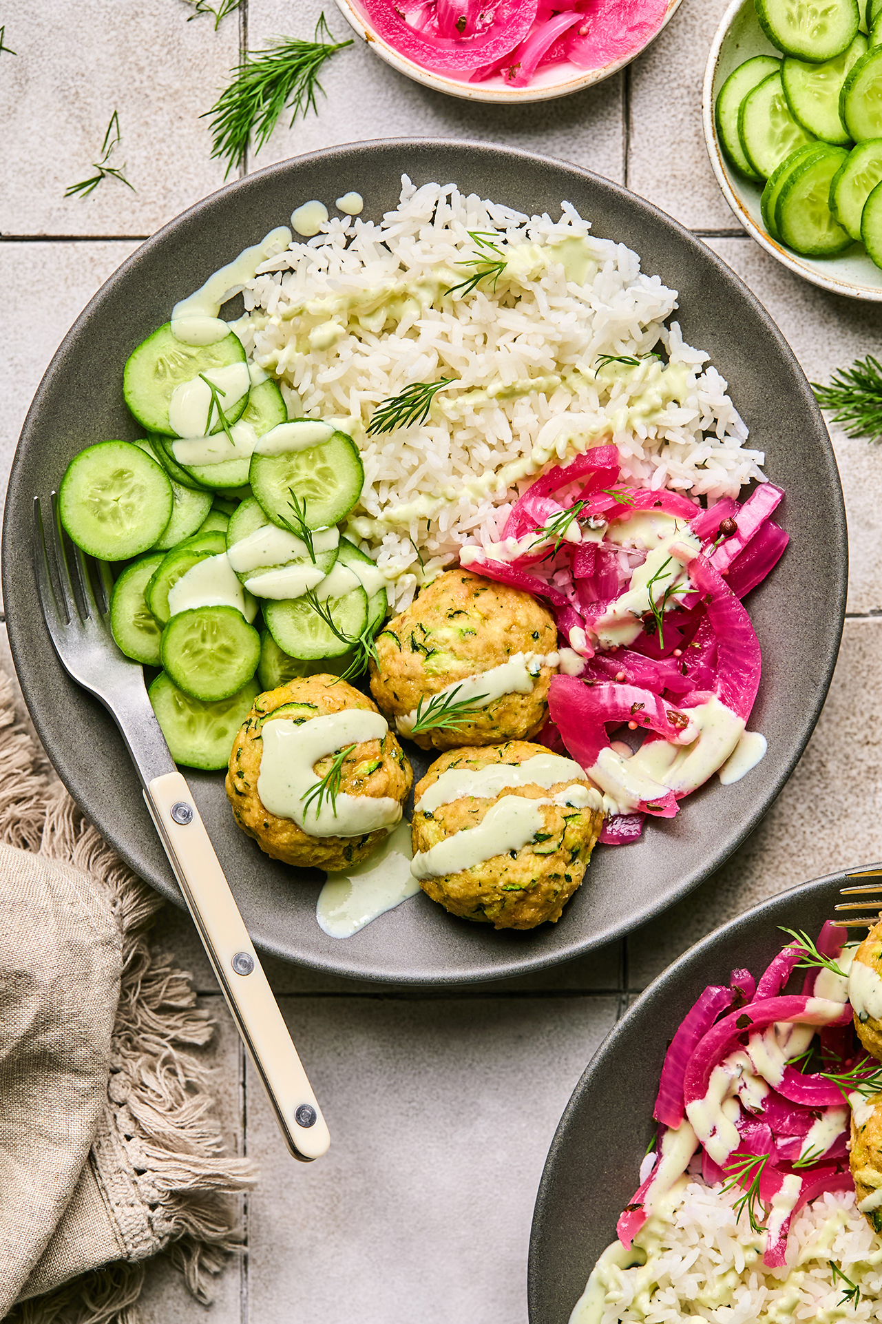 turkey feta meatballs in a bowl with cucumber, rice, and pickled onion, topped yogurt sauce