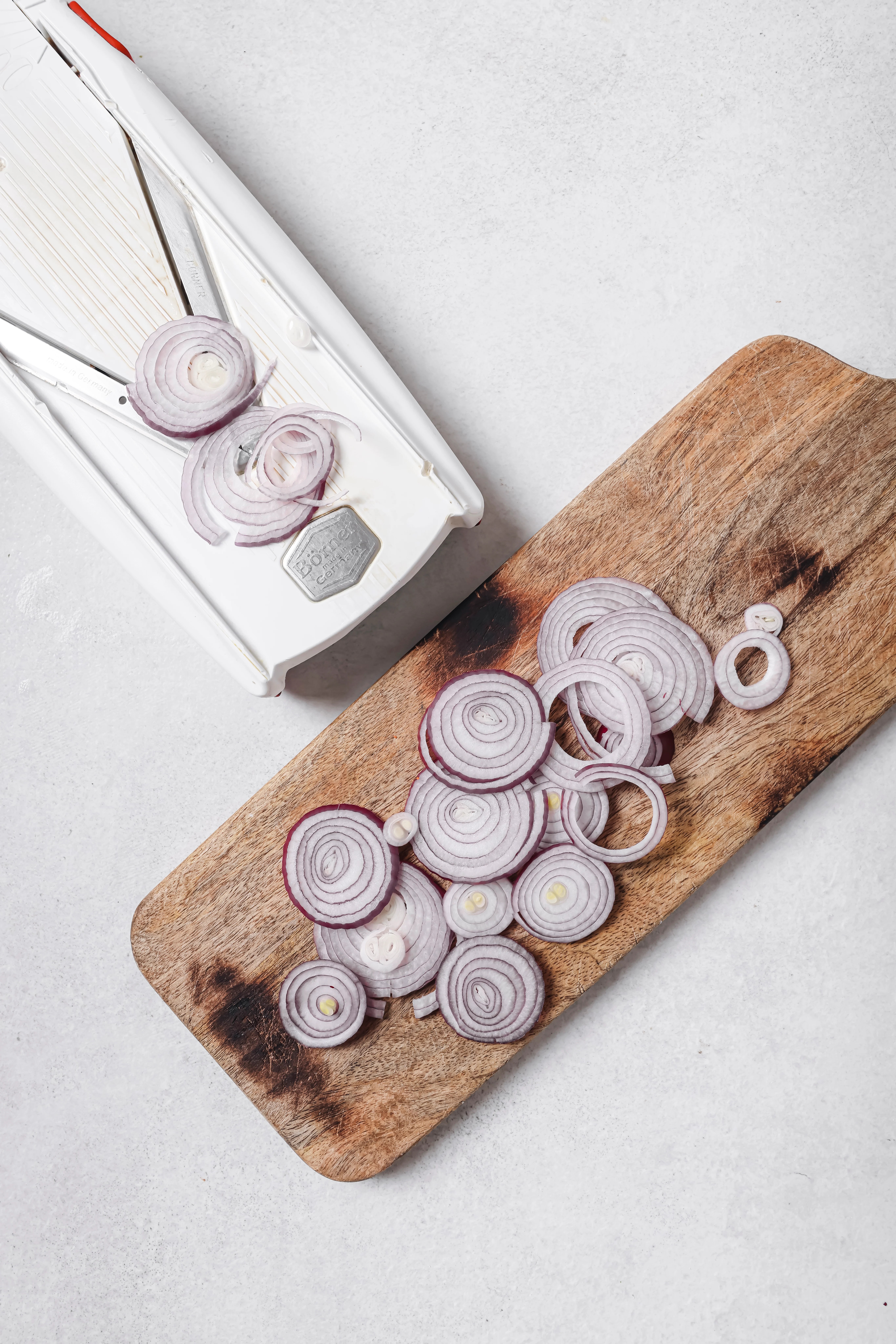 mandolin with red onions, sliced on a cutting board