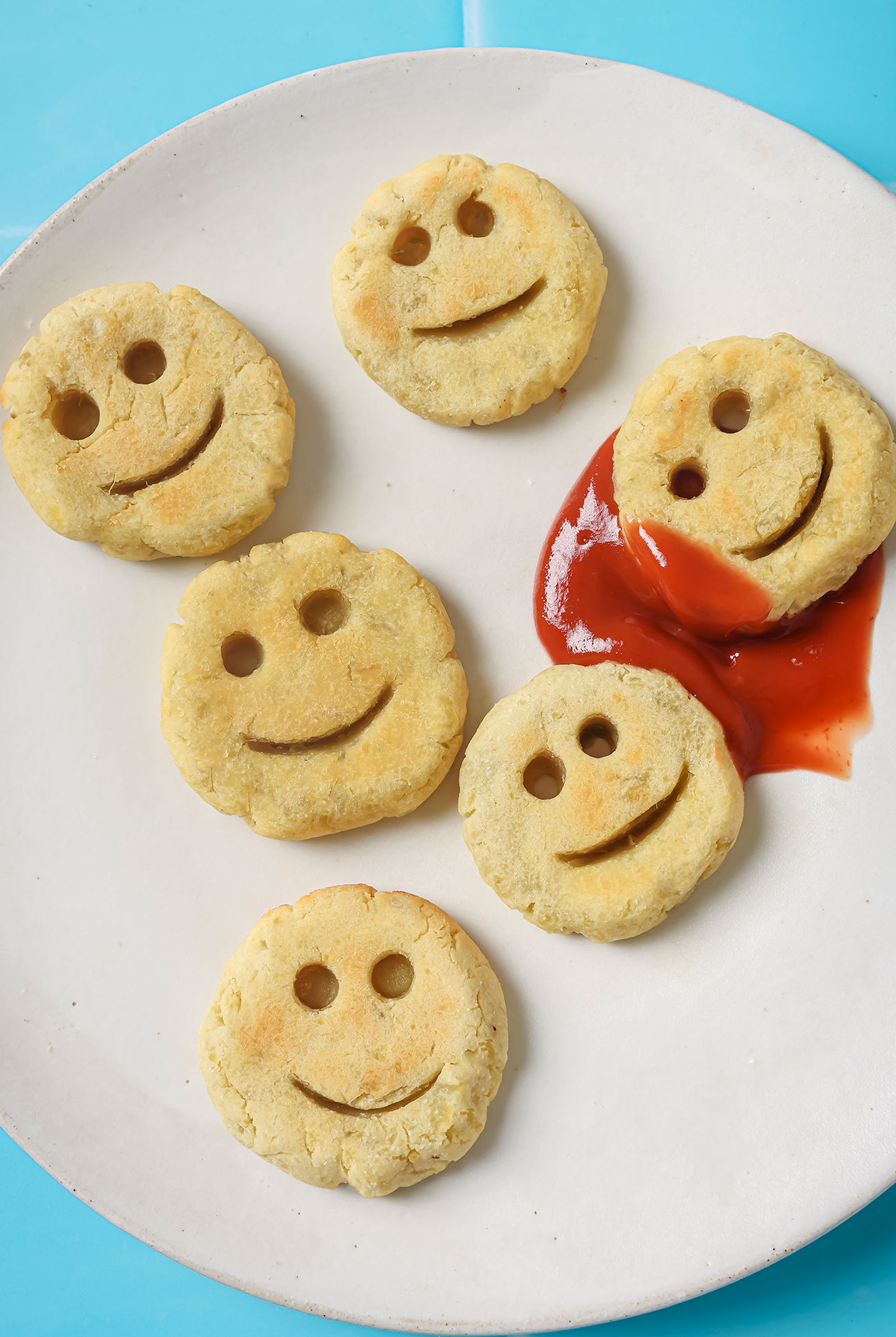 Sweet potato smiley fries on a white plate with ketchup.