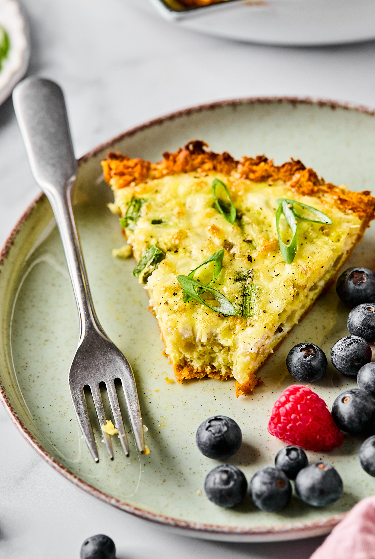 A slice of sweet potato quiche with a bite taken out of it and a fork.