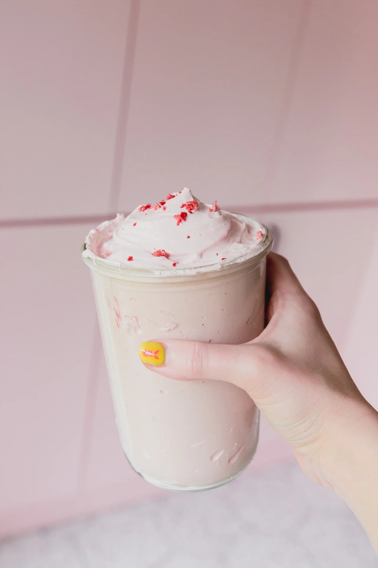 A hand holding a jar of strawberry marshmallow fluff.