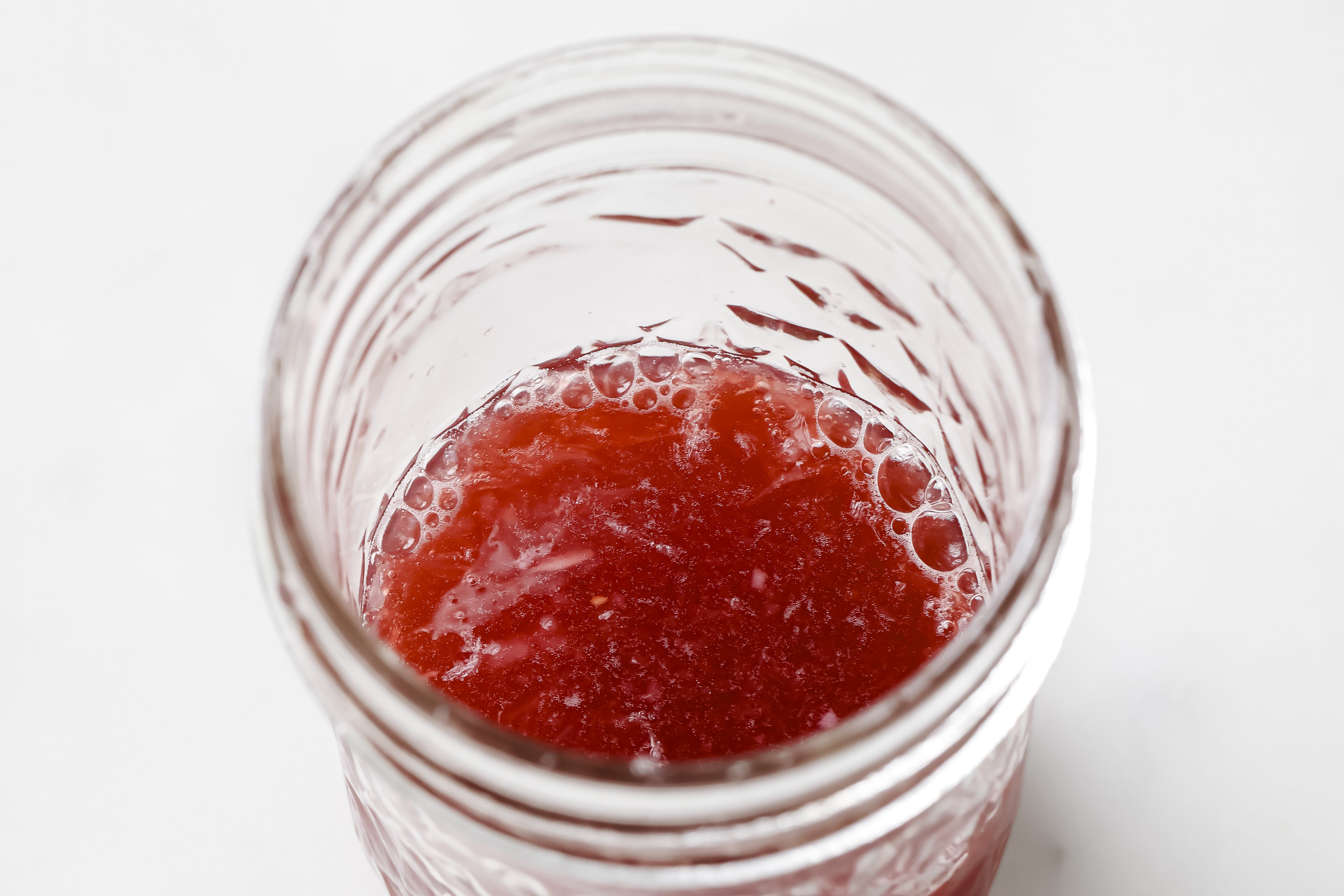 A glass jar filled with an apple cider vinegar shot.