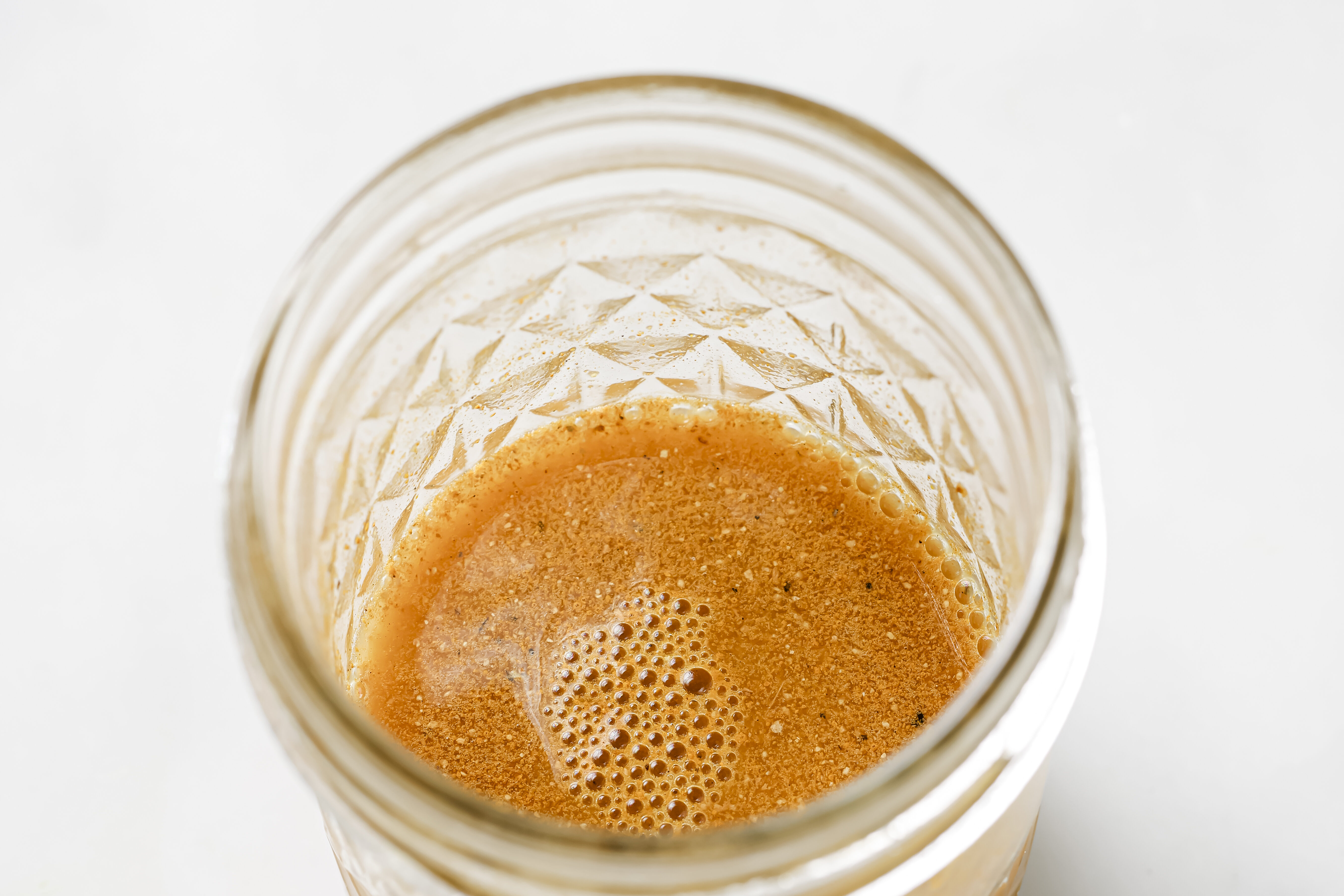A glass jar filled with an apple cider vinegar shot.