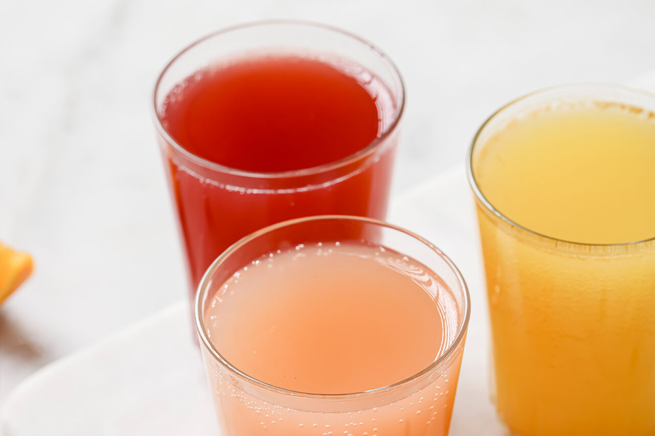 Three glasses filled with different flavors of apple cider vinegar shots.