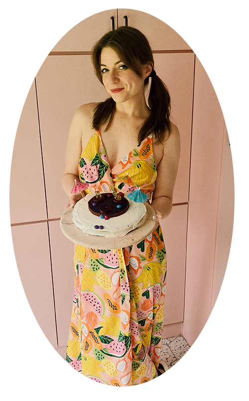 Food blogger, Michelle Hoover in a pink kitchen holding a swimming pool cake on a plate.