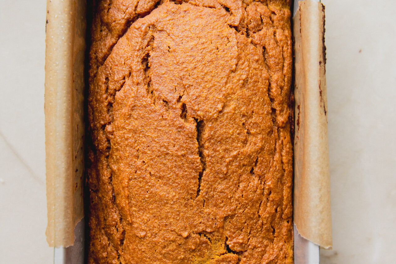 Pumpkin bread cooked in a loaf pan with parchment paper.