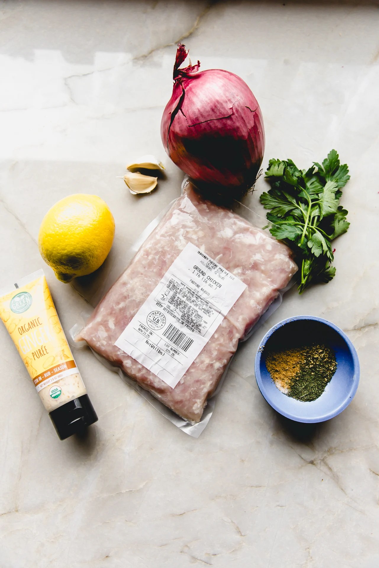 Sheet pan kebab ingredients laid out on a marble counter top.