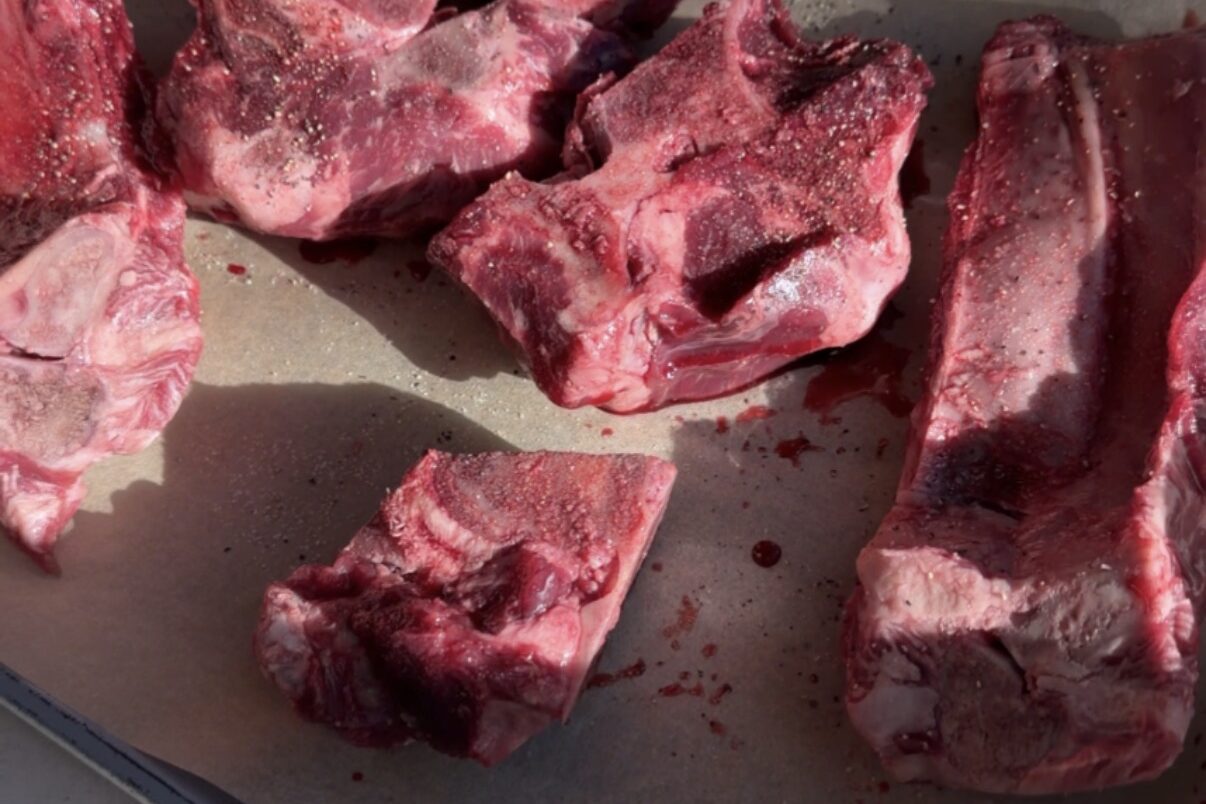 Meaty beef bones on a parchment lined baking sheet.