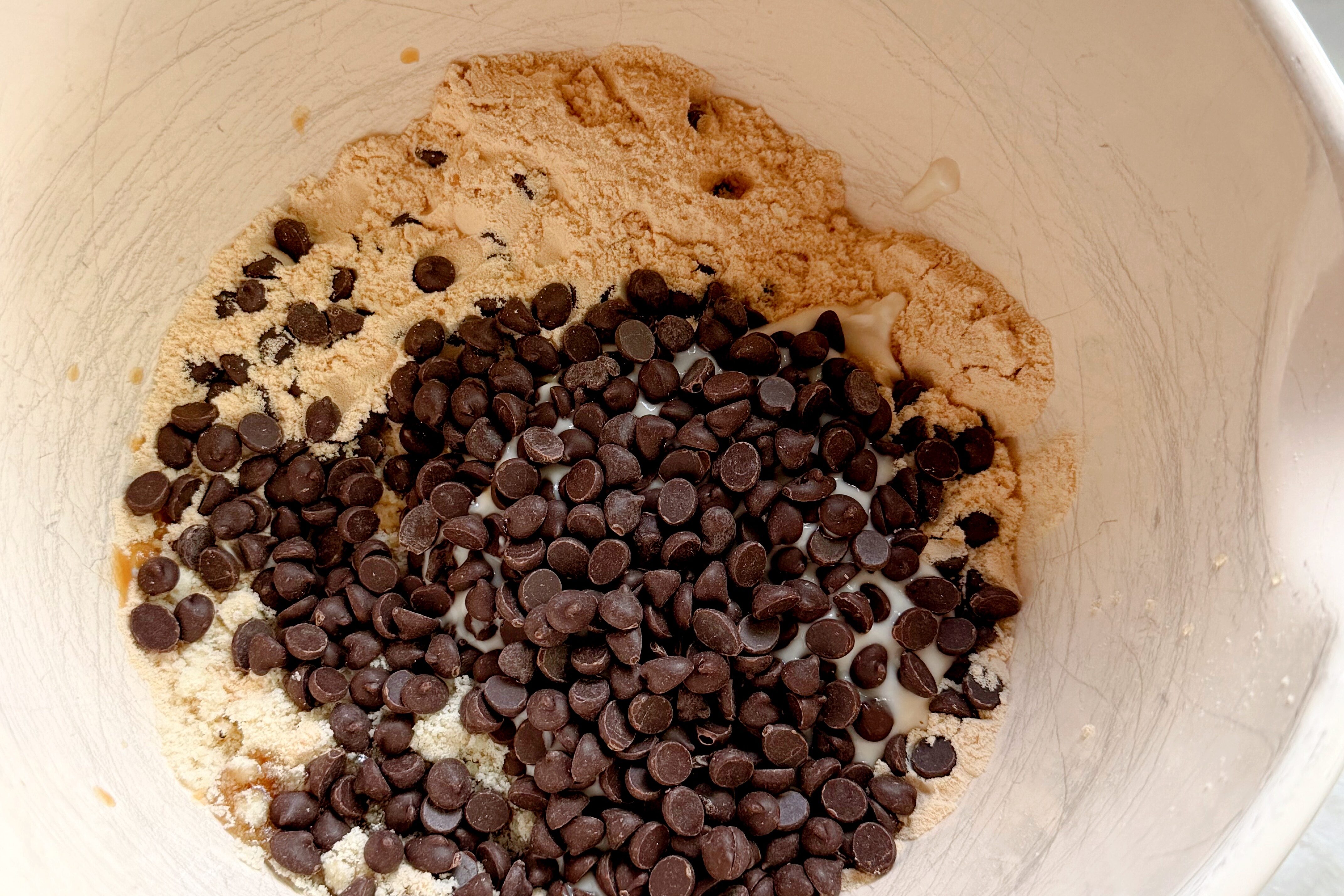 A white bowl filled with all the ingredients for protein cookie dough before mixing it together to form the dough.