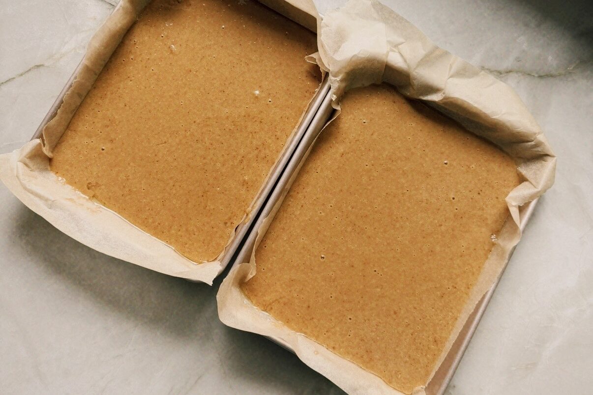Two rectangular cake pans with cake batter.