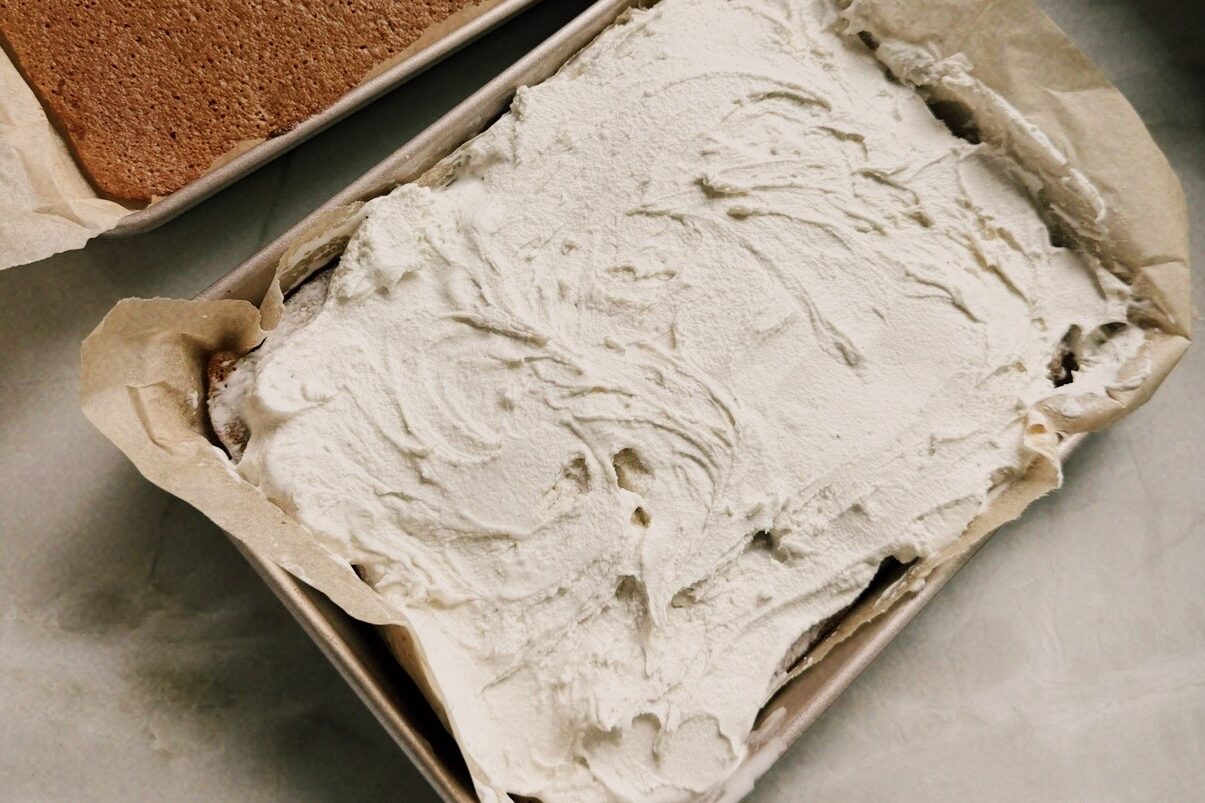 Two rectangular cake pans with cake, and one topped with ice cream.